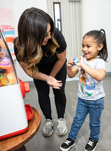 A child together with one of our assistants in a prize Checkout machine at Just For Kids Dentistry & Orthodontics