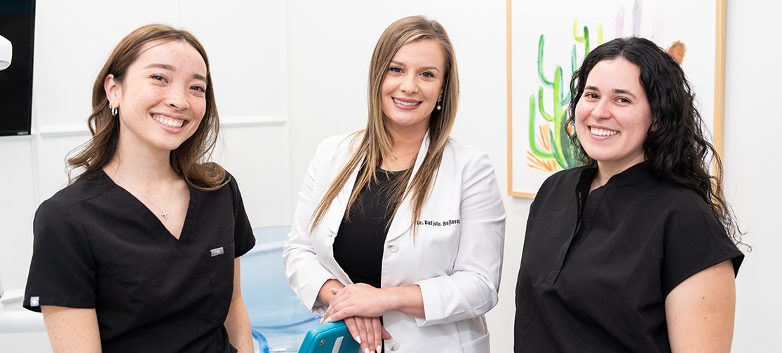 Orthodontist with two of our dental assistants standing smiling in the operating room